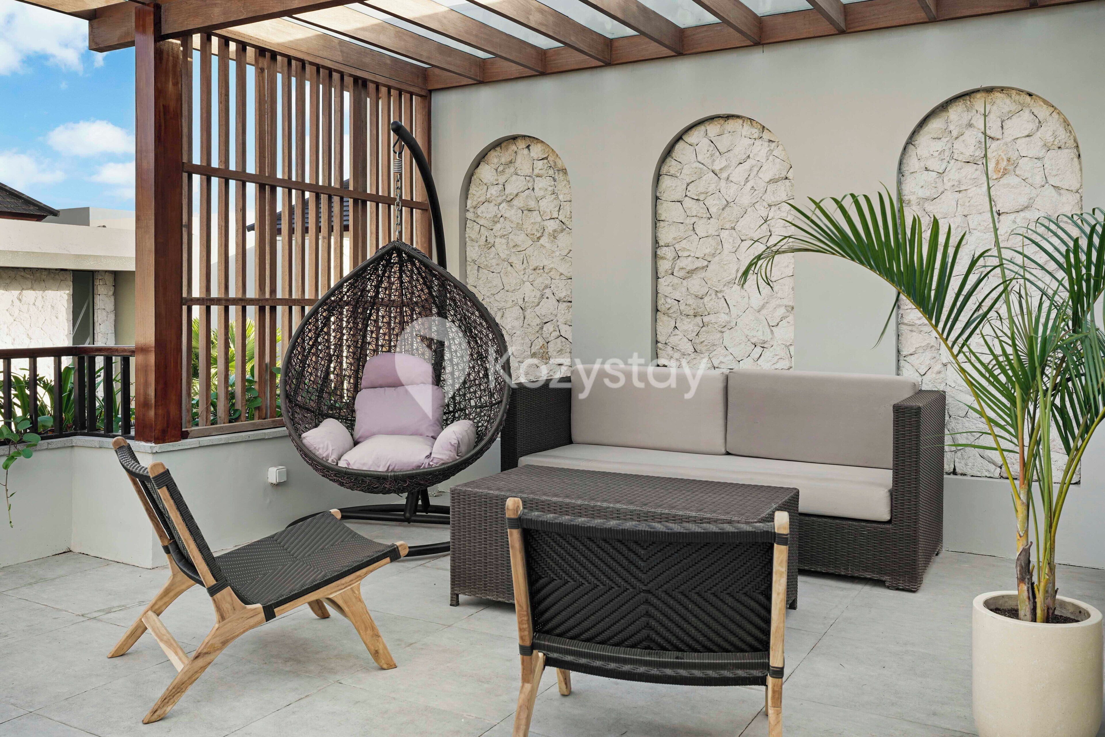 A patio with wicker furniture, a cushioned hanging chair, and a potted plant.