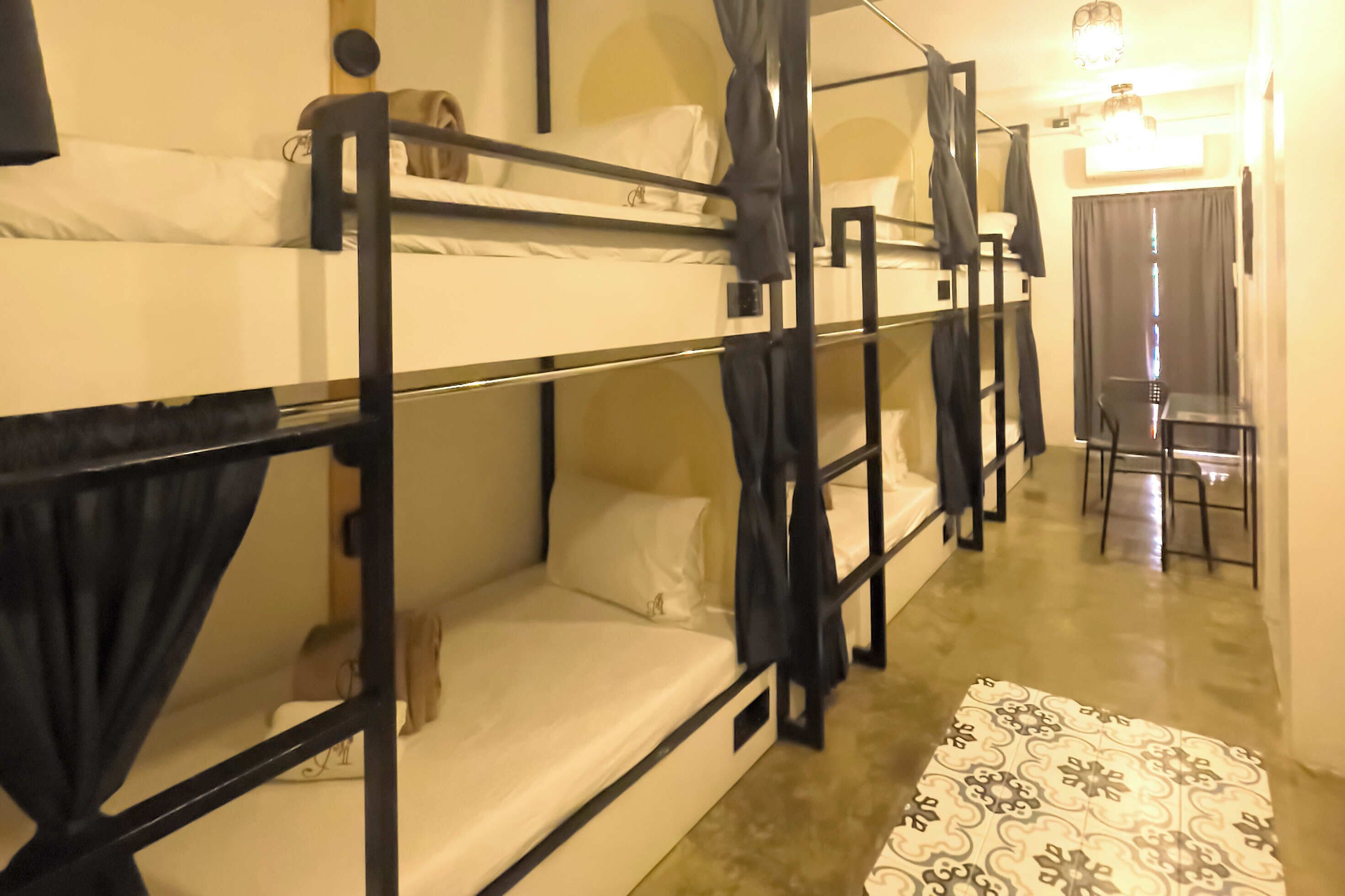Habitación tipo dormitorio con literas, un escritorio pequeño y una alfombra estampada.