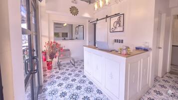 A modern kitchen with white cabinets, a wooden countertop, and a backsplash with a clock.