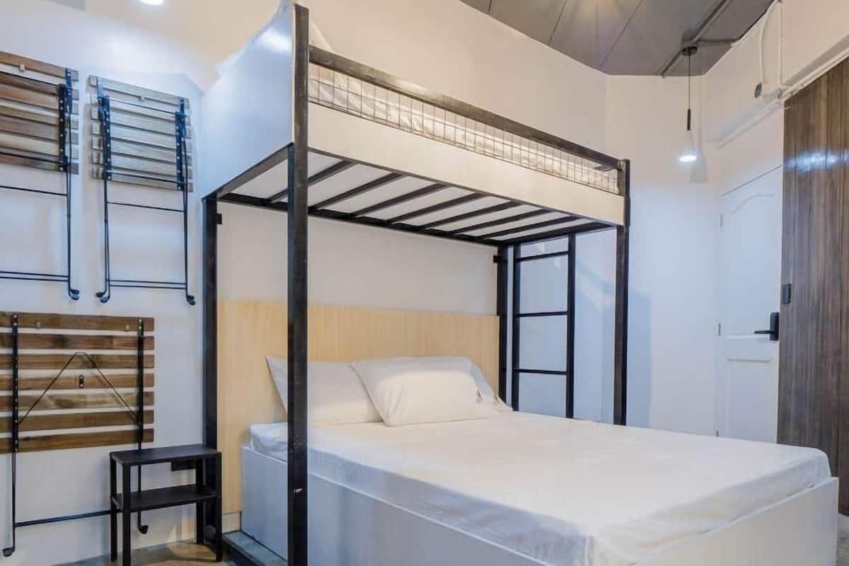 Un letto a castello con una testiera in legno, un tavolino e un tappeto grigio su un pavimento in pietra.