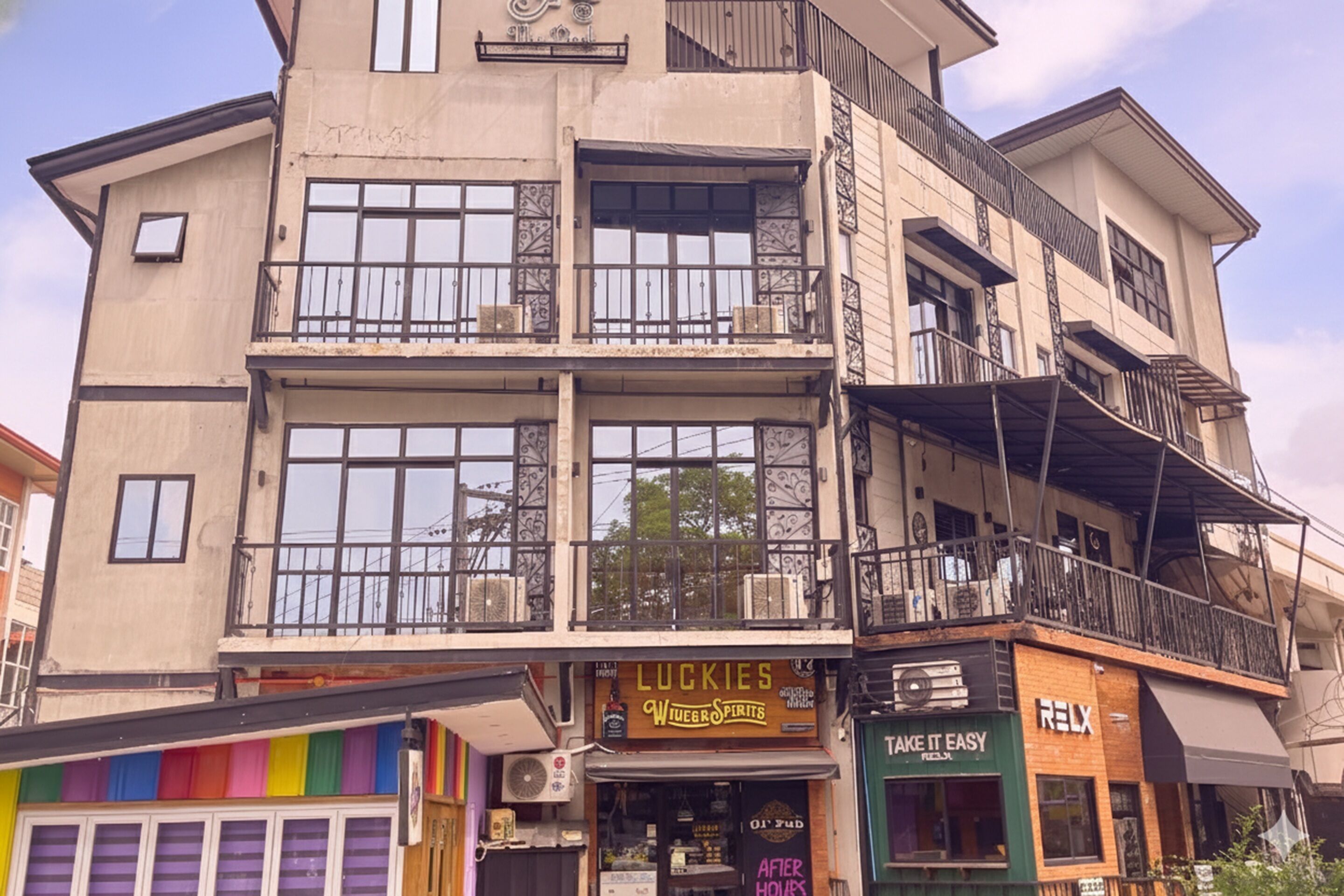 A multi-story building with balconies, a storefront with a sign reading "LUCKIES," and a shop with a sign reading "TAKE IT EASY."