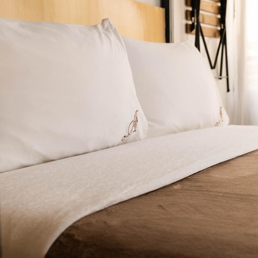 A bed with white linens and a wooden headboard.