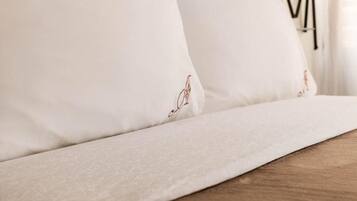 A bed with white linens and a wooden headboard.