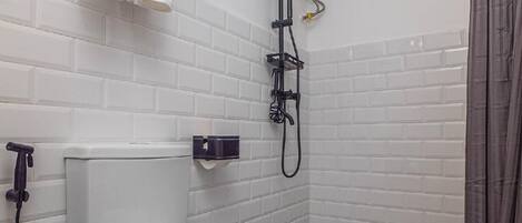 A modern bathroom with a toilet, a shower, and a towel rack with towels.
