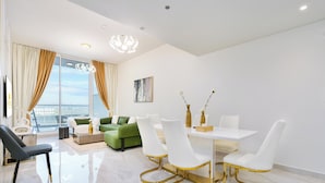 Un salon moderne avec un canapé vert, des chaises de salle à manger blanches et une table blanche.