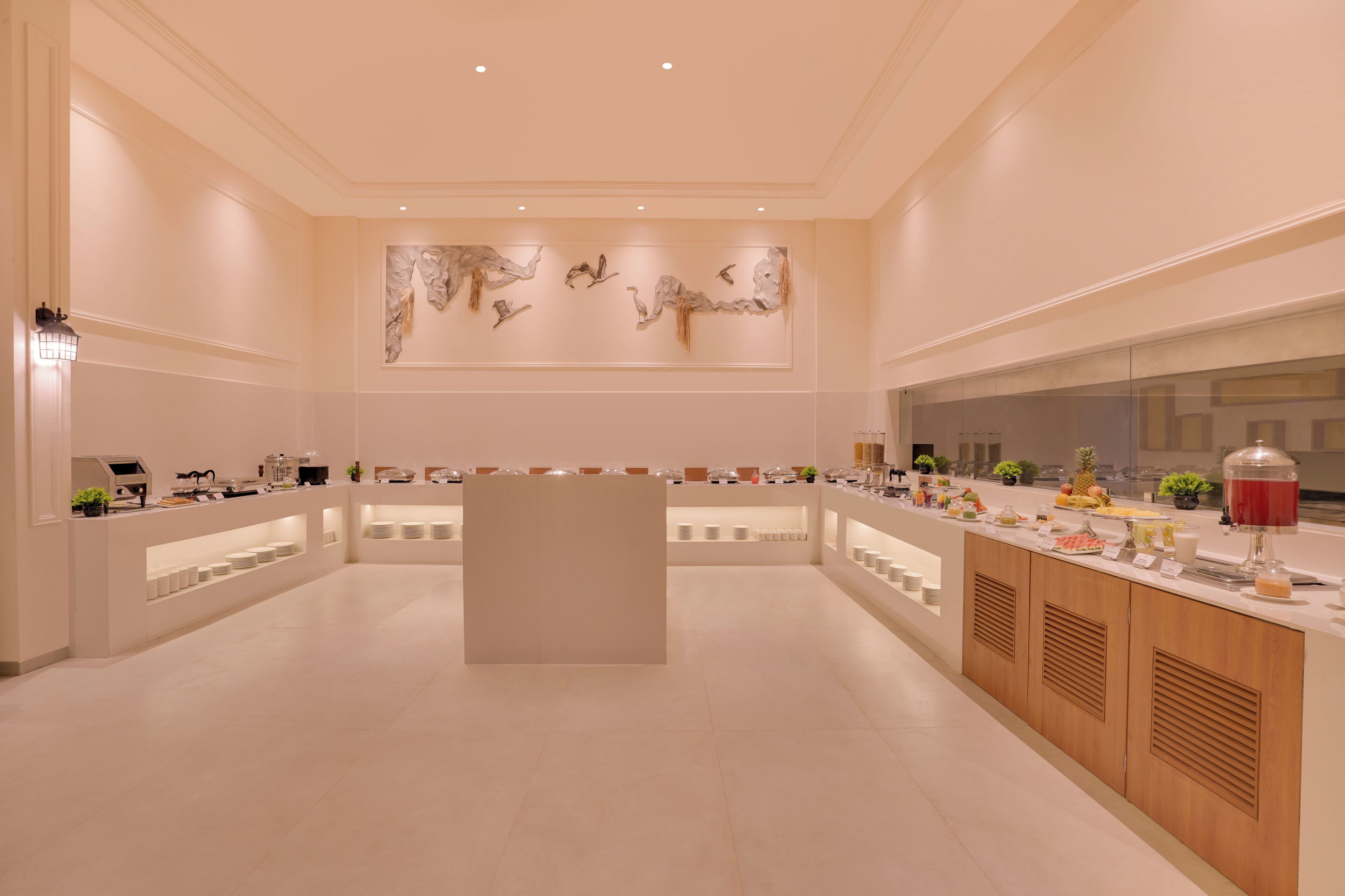 Un hall d’hôtel spacieux et moderne, doté d’un comptoir d’accueil central, d’une grande œuvre d’art abstrait au mur et de diverses commodités, notamment un distributeur de boissons et un présentoir de fruits.