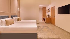 Een hotelkamer met twee bedden, een tv die aan de muur is bevestigd, en een houten deur naar een badkamer.