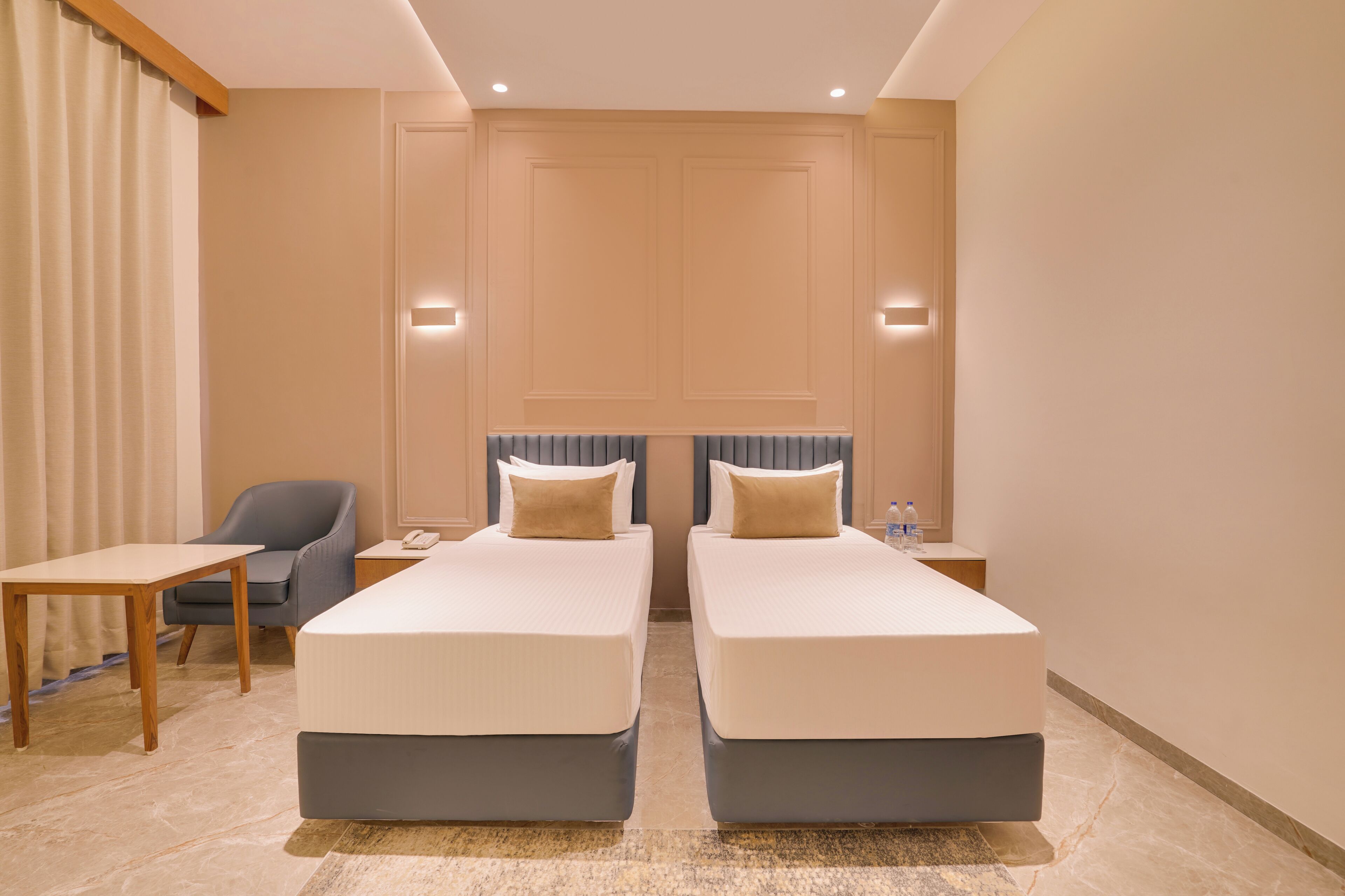 A hotel room with two beds, a desk, a chair, and a bathroom.