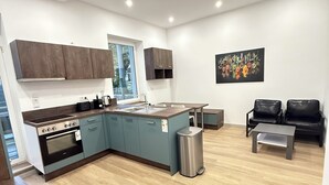 Cozinha moderna com forno embutido e área de refeições com uma mesa pequena e duas cadeiras.
