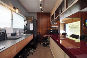 A modern kitchen with a wooden countertop, a refrigerator, a microwave, and a sink. There is a small dining area with a table and chairs.