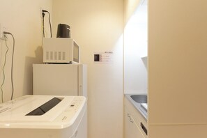 Un área de lavandería compacta con lavadora, secadora y un microondas sobre una pequeña encimera.