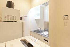 Een koelkast, een magnetron, een kookplaat, kookgerei, borden en bestek