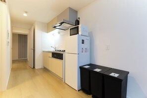 Een koelkast, een magnetron, een kookplaat, kookgerei, borden en bestek