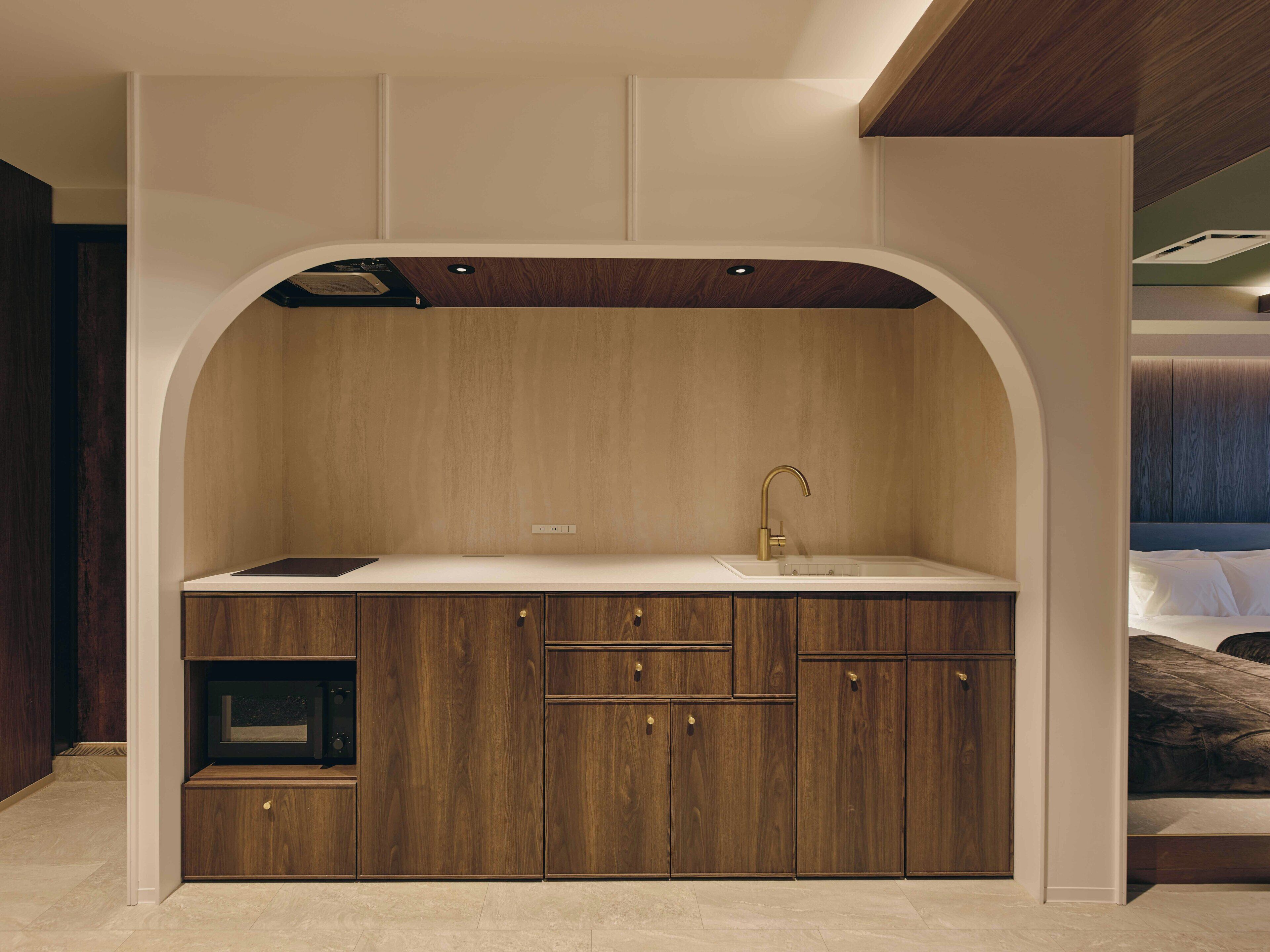 A compact kitchen with a built-in sink, wooden cabinetry, and a small countertop.