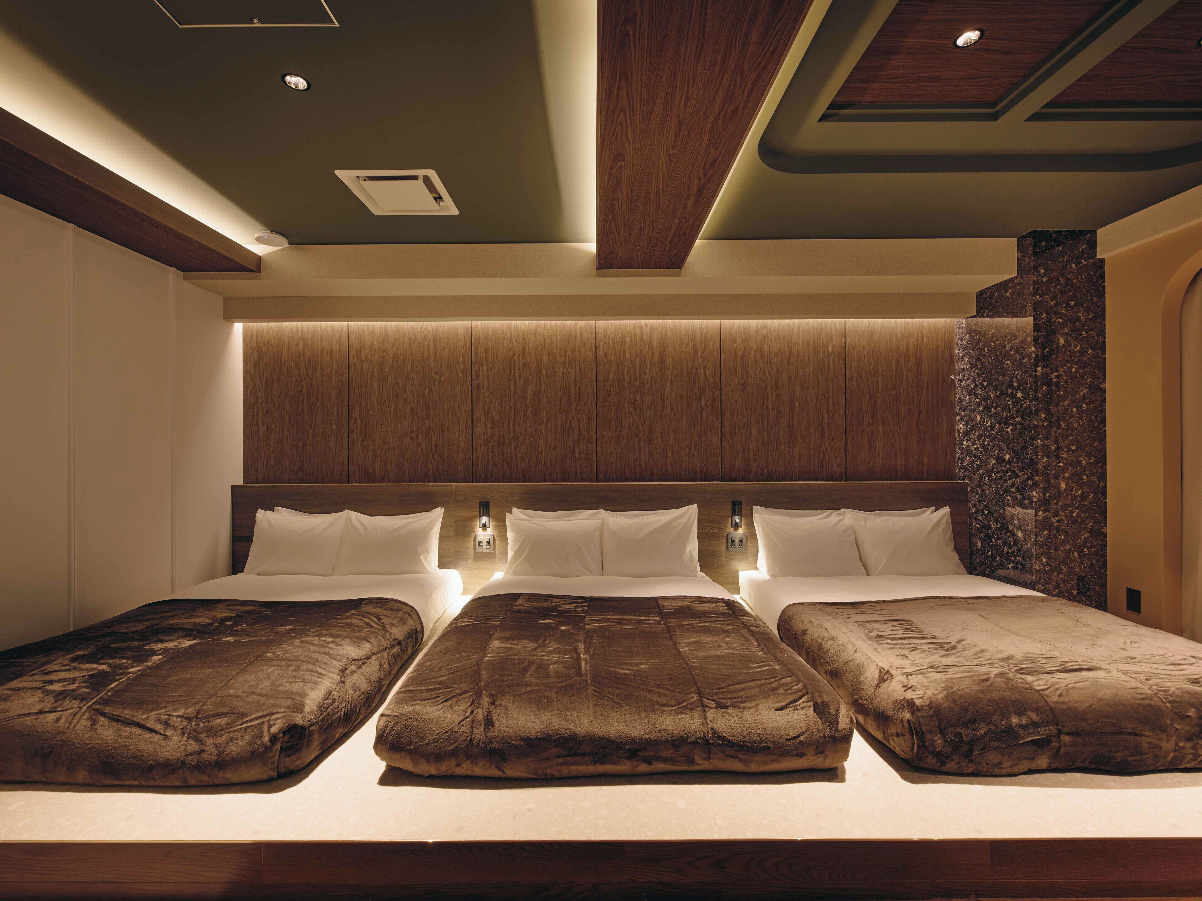 A large, well-lit bedroom with a wooden headboard, a stone accent wall, and a modern design.