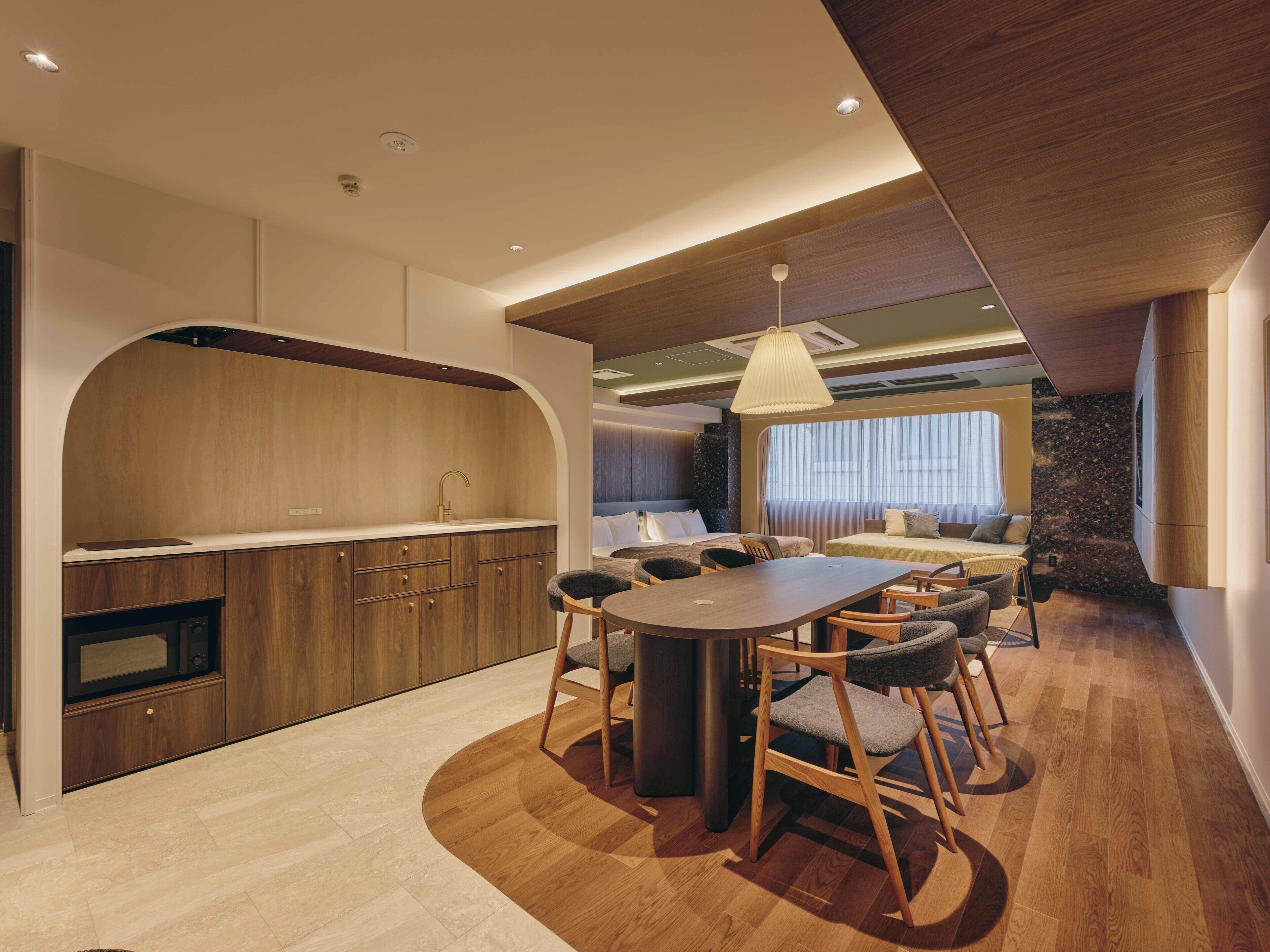 Habitació d'hotel moderna amb cuina, zona de menjador i un llit gran.