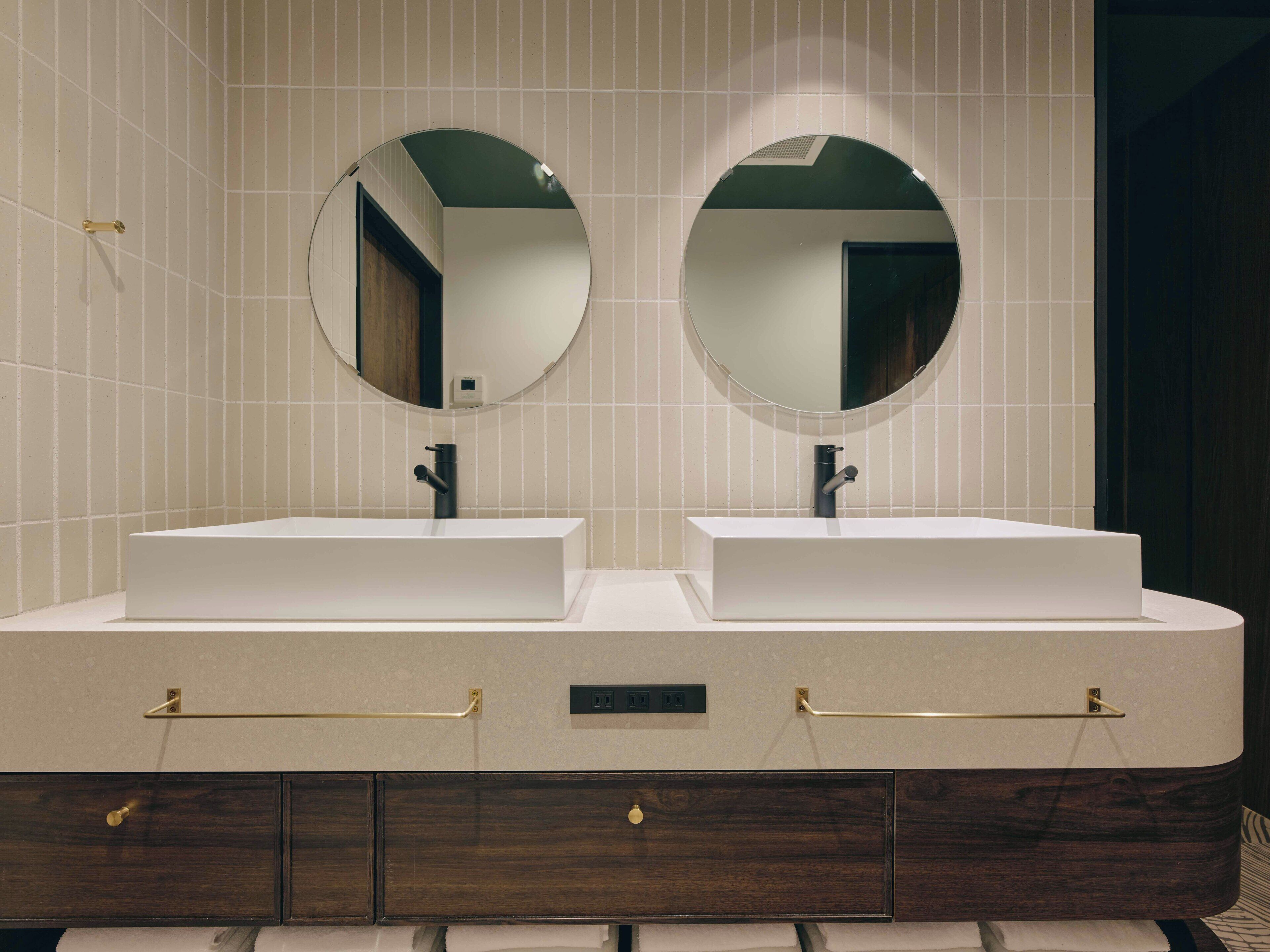 A bathroom with two sinks, a mirror above each sink, and a wooden vanity with drawers.
