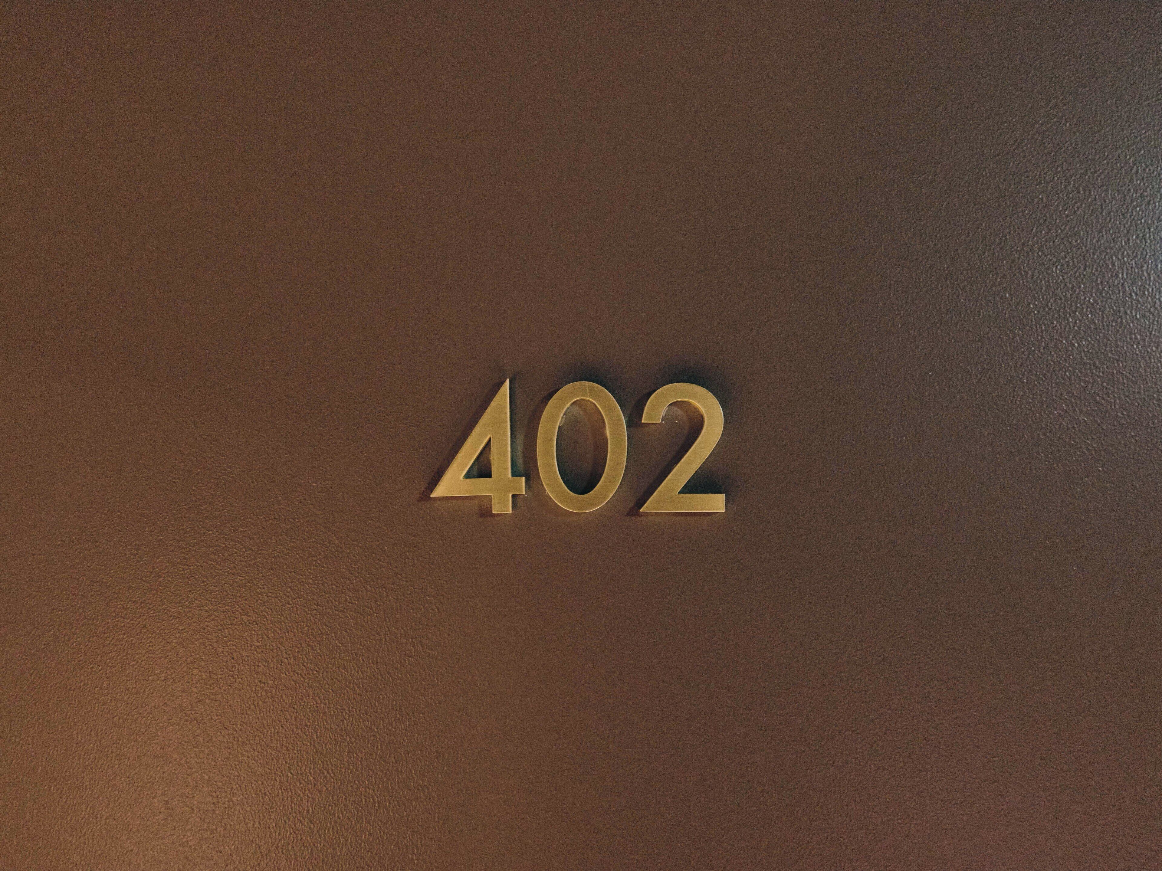 A close-up of the number "402" embossed on a brown leather surface.