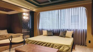 A modern bedroom with a large bed, a wooden nightstand, a chair, and a large window with curtains.
