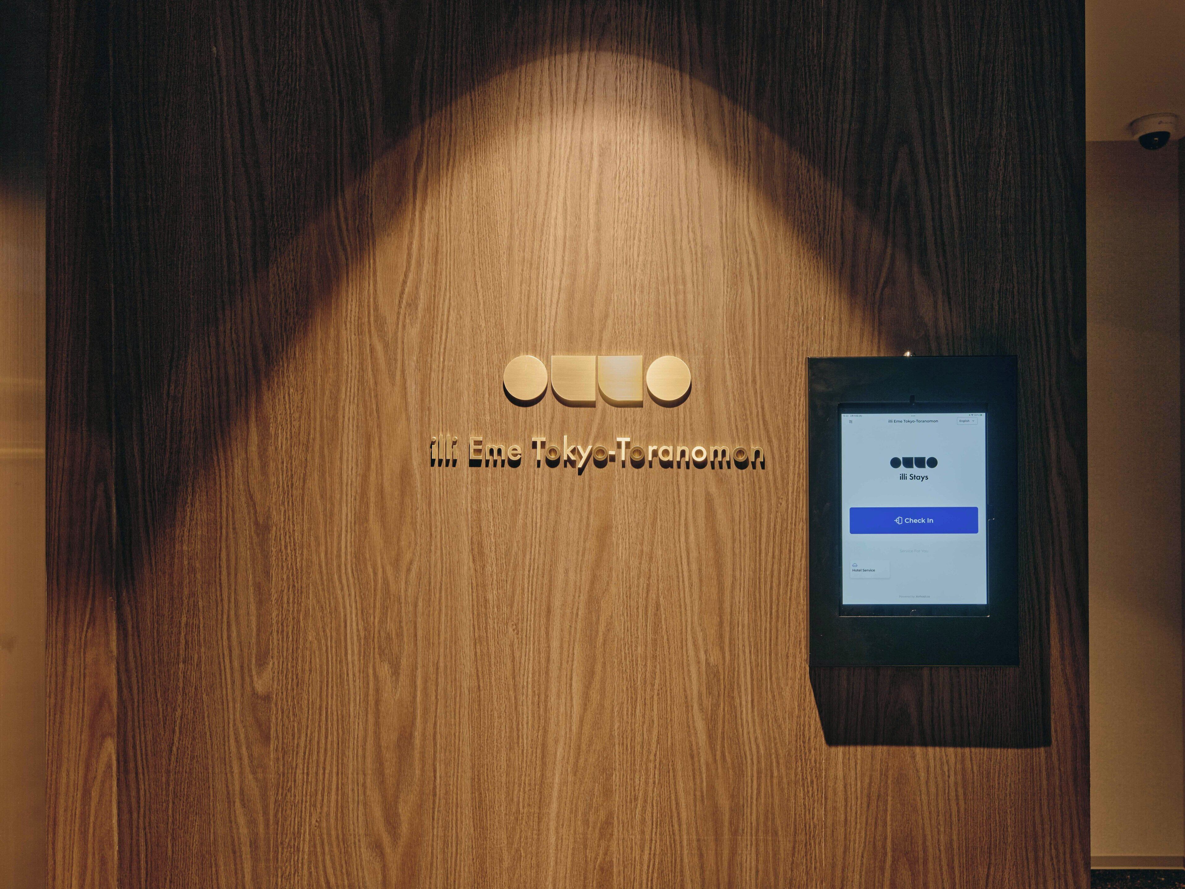 Una porta in legno con un cartello che riporta la scritta "iLLi Eme Tokyo-Toranomon".