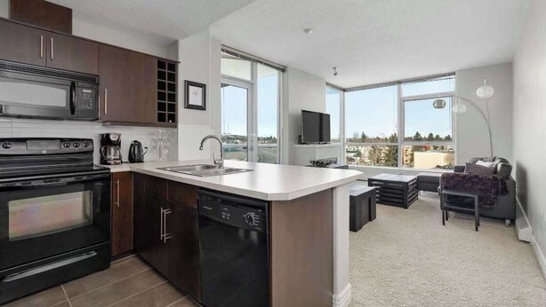 Una cocina moderna con una isla central, electrodomésticos integrados y grandes ventanales con vistas a la ciudad.