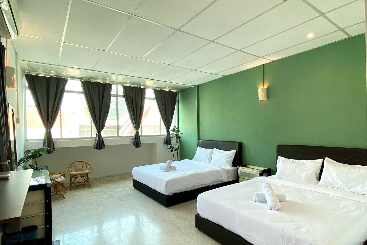 A hotel room with two beds, a desk, a chair, and a window with curtains.