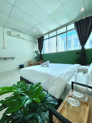 A hotel room with a large bed, a window with curtains, a potted plant, and a tray with glass jars. - Sembilan Inn by Soft loft (George Town)