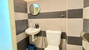 A bathroom with a toilet, sink, and mirror. - Sembilan Inn by Soft loft (George Town)