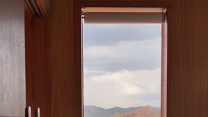 Eine Holztür, die auf einen Blick über einen See, einen Hügel und eine zylindrische Struktur eröffnet.