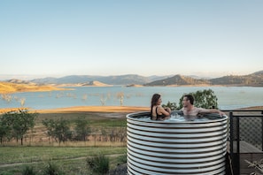 Een hottub met een prachtig uitzicht over een meer en heuvels.
