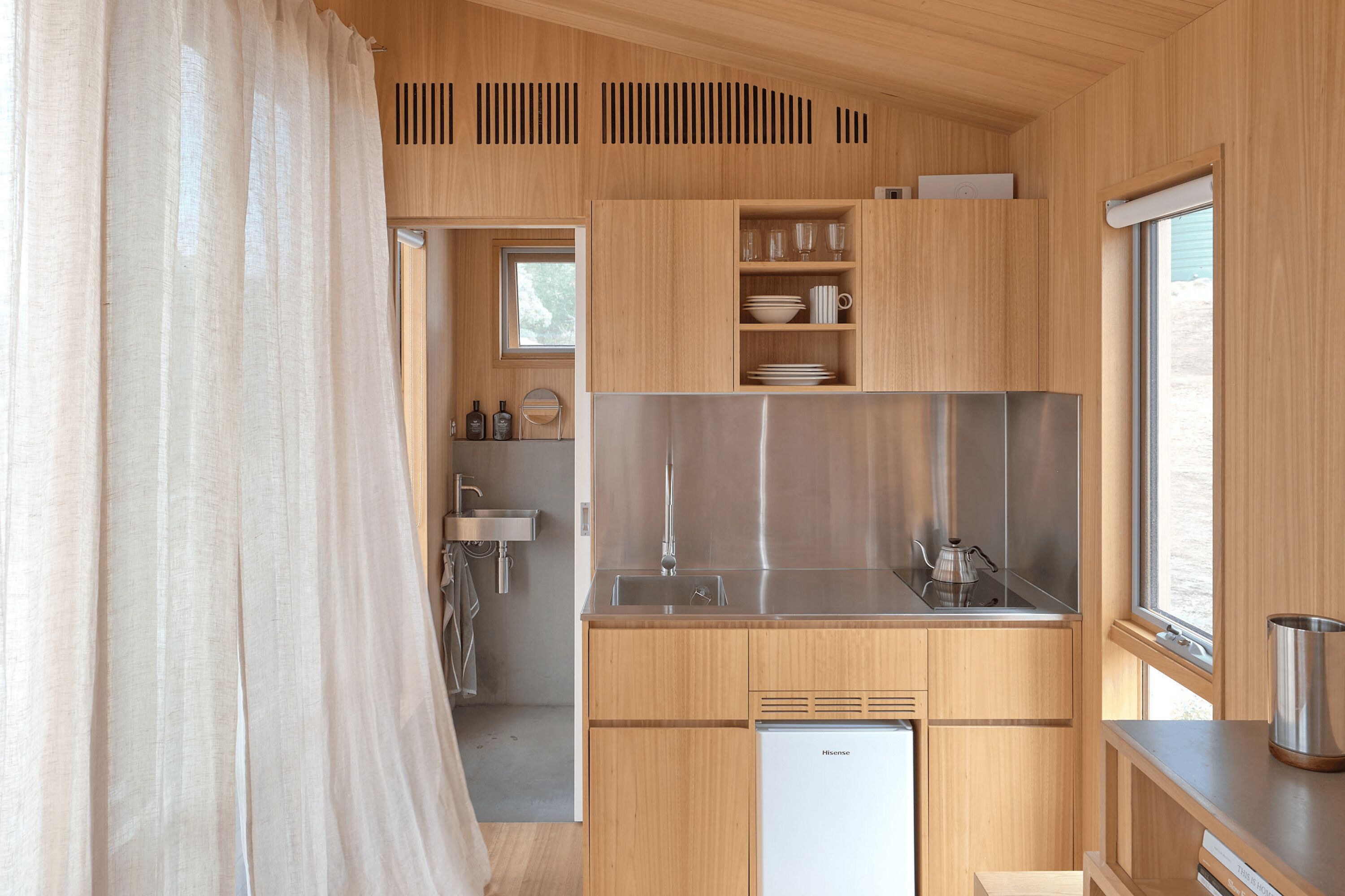 Una cocina compacta con armarios de madera, un refrigerador de acero inoxidable y una ventana.