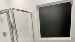 Ein modernes Badezimmer mit Duschkabine aus Glas, einer großzügigen Badewanne und einem am Wand montierten Fernseher.