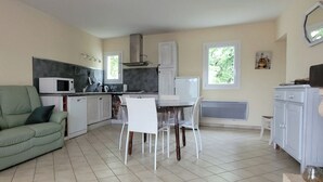 A compact kitchen with a dining area, a green sofa, and a white cabinet. - Quiet, detached house close to shops and hiking trails. (Forcalquier)