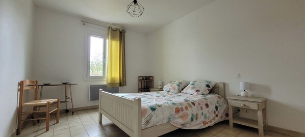A bedroom with a bed, a chair, a desk, and a window with curtains. - A quiet, detached house near shops and hiking trails. (Forcalquier)