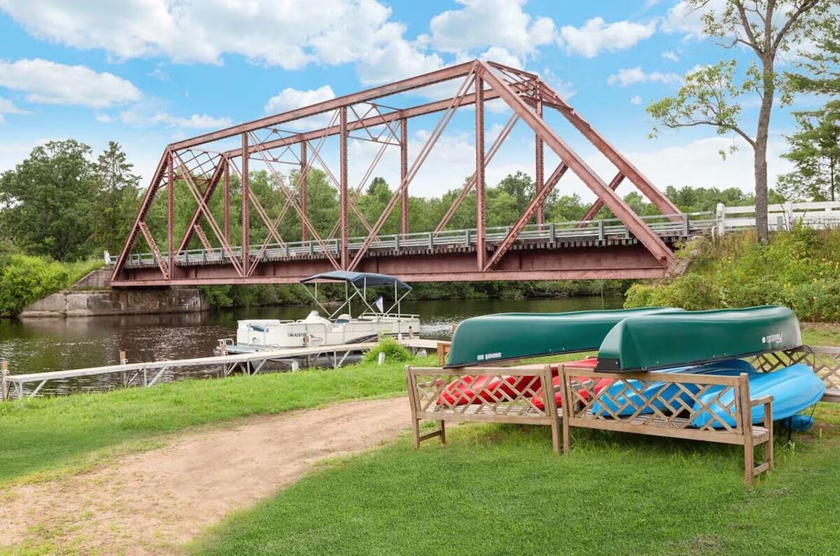 A metal bridge over a river with boats docked nearby.