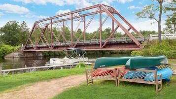 A metal bridge over a river with boats docked nearby.
