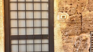 A window with a metal grid design, a brick wall, and a small plaque with the number "62". - Cozy in the historic center of Palermo 300mt from the train station (Palermo)