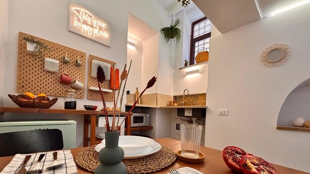A modern kitchen with a dining area, featuring a pegboard wall, a neon sign, and a potted plant. - Cozy in the historic center of Palermo 300mt from the train station (Palermo)