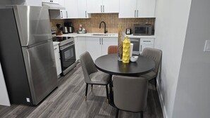 A modern kitchen with stainless steel appliances, a round dining table, and grey chairs. - Self place to enjoy it (Edmonton)