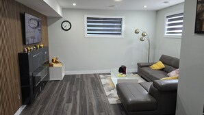 A modern living room with a grey sofa, a glass coffee table, and a wooden entertainment unit. - Self place to enjoy it (Edmonton)