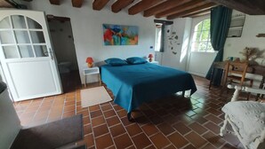 A bedroom with a bed, a painting, a window, and a door.