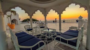 A terrace with white columns, blue cushioned chairs, and a glass table. - Penthouse with pool and ocean view just a few steps from the beach (San Francisco)
