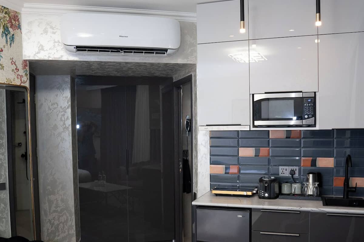 A modern kitchen with a microwave, toaster, and coffee maker. There is a white table with salt and pepper shakers.