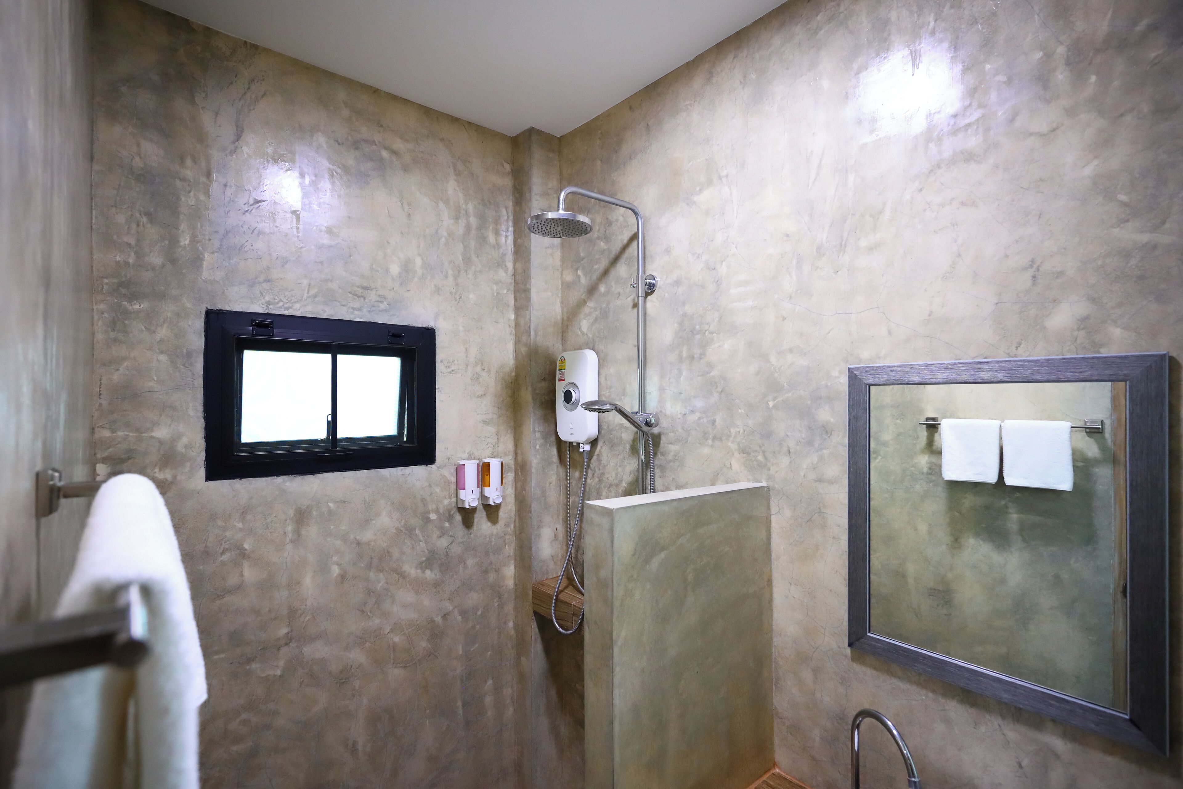 A bathroom with a shower, a mirror, and a towel rack.