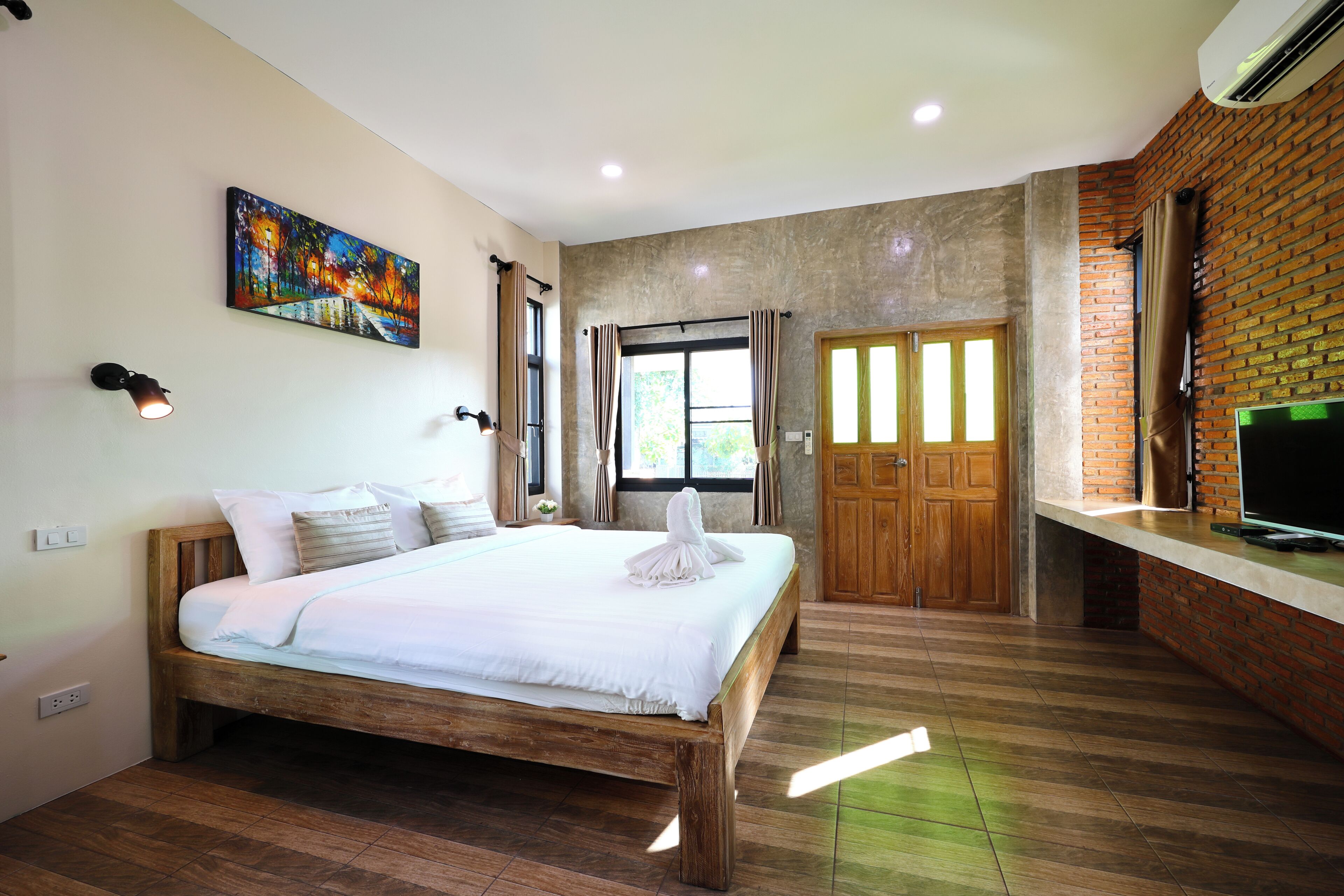Un dormitorio con una cama de madera, un cuadro en la pared, un televisor sobre un mueble y una pared de ladrillo.