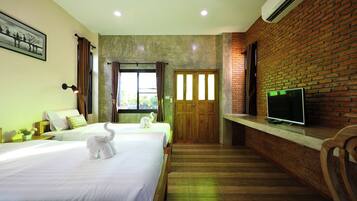 A hotel room with two beds, a TV, a brick wall, and a window with curtains.