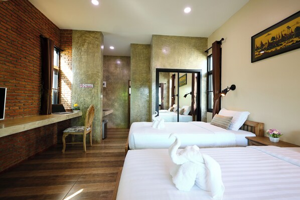 Habitación de hotel con dos camas, un escritorio, una silla y una pared de ladrillo.