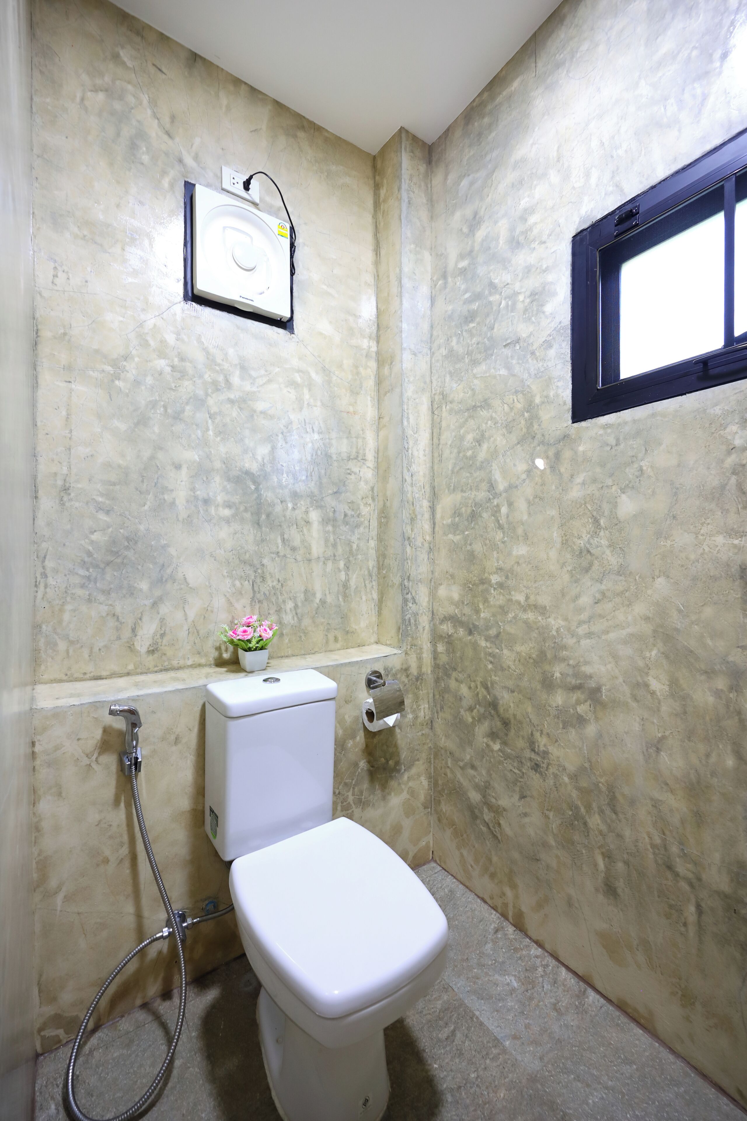 A bathroom with a toilet, a shower, and a small window.