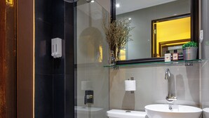 Een moderne badkamer met een glazen douchecabine, een wit toilet en een wastafel met spiegel erboven.