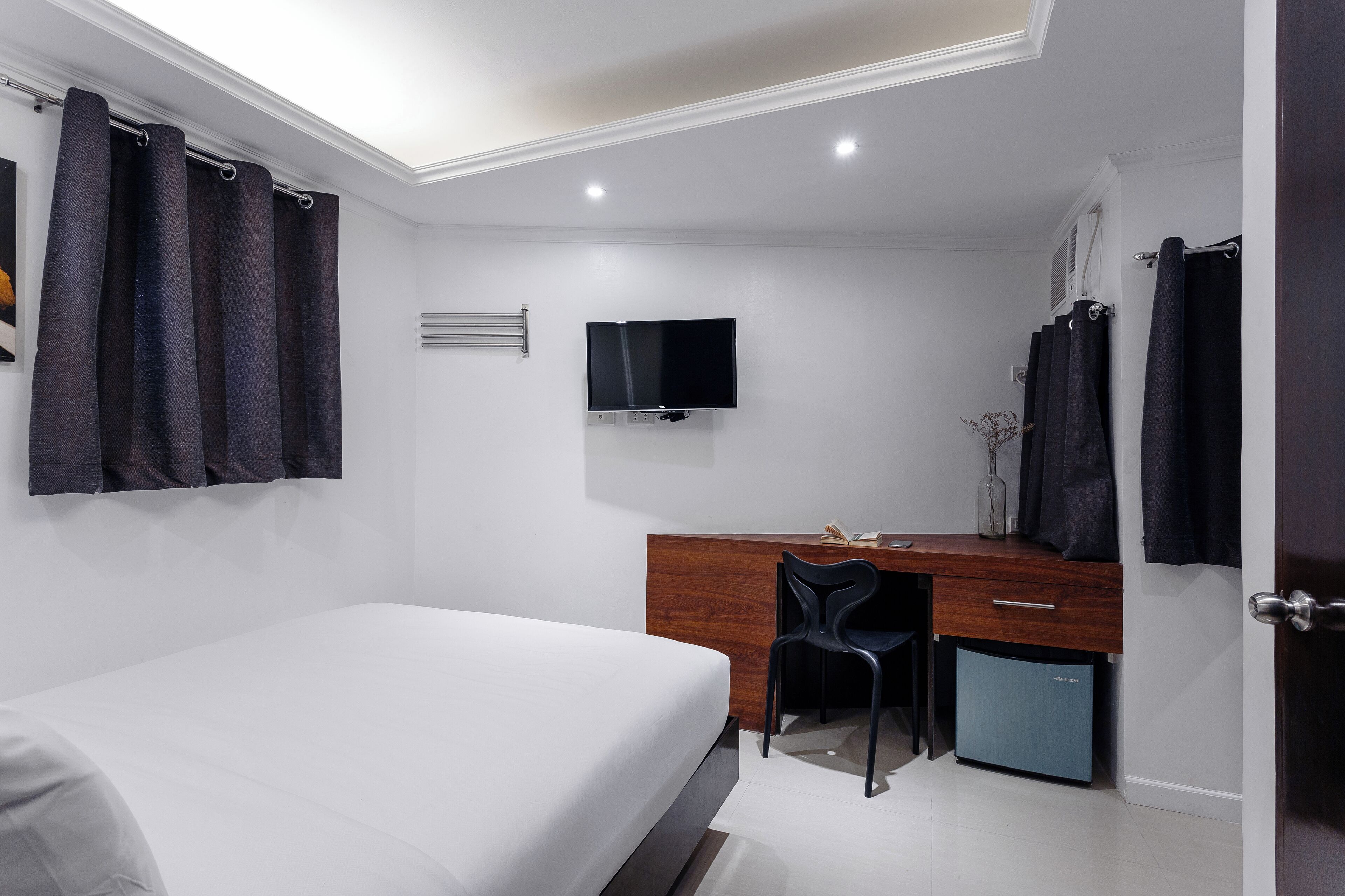 Un dormitorio con cama, escritorio y televisor.